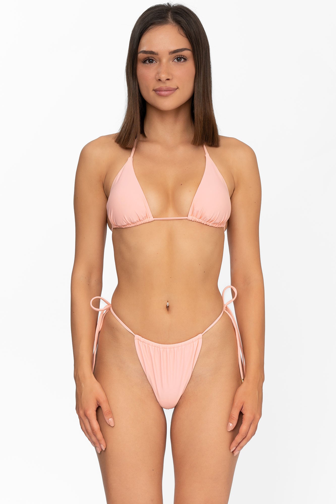 Front view of model wearing matching sunset peach Mila triangle bikini top and string bikini bottom by Aventura Swimwear. 