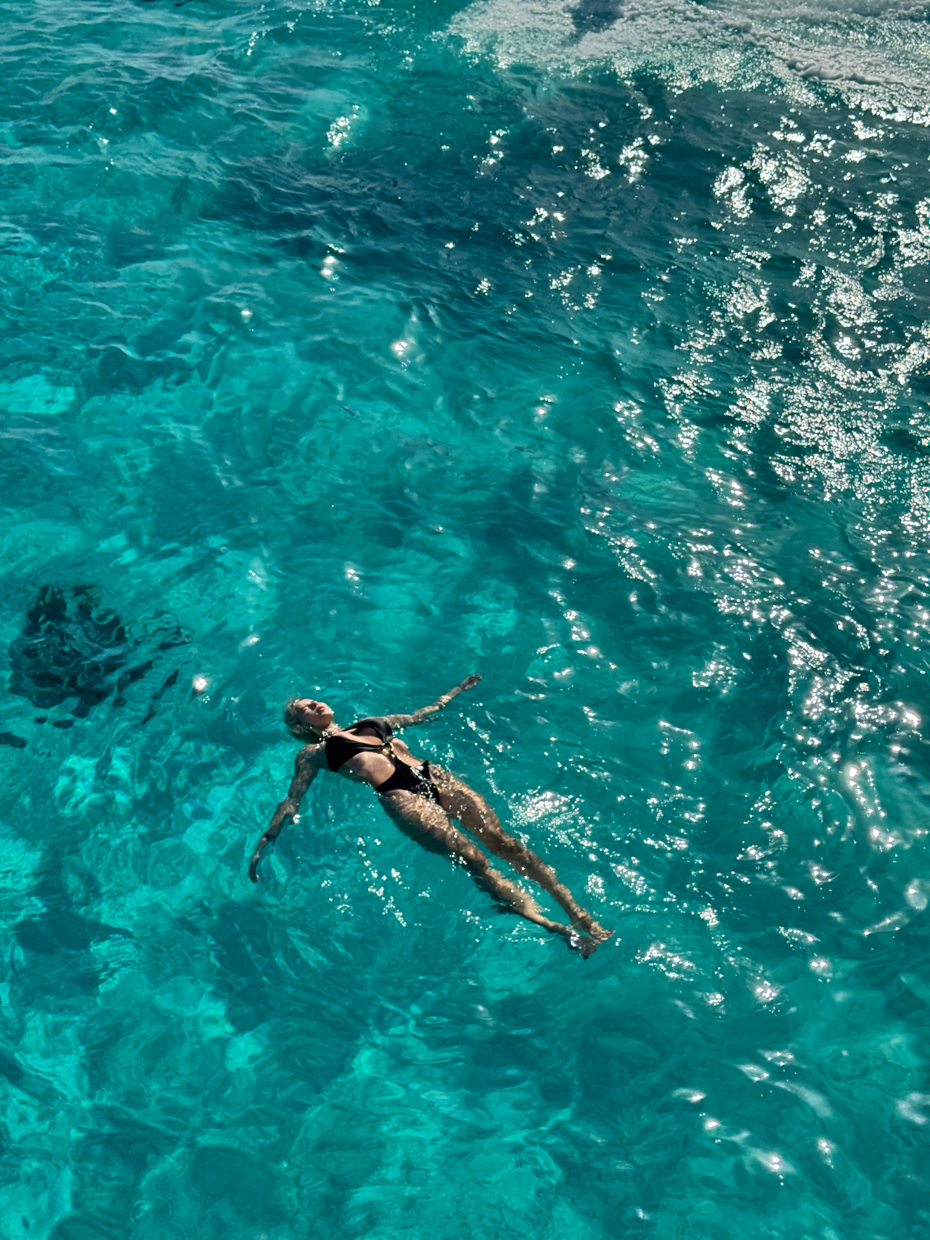 Lina relaxes in crsytal clear waters in the Petra Swimsuit in Black whilst enjoying a boat trip in Soma Bay