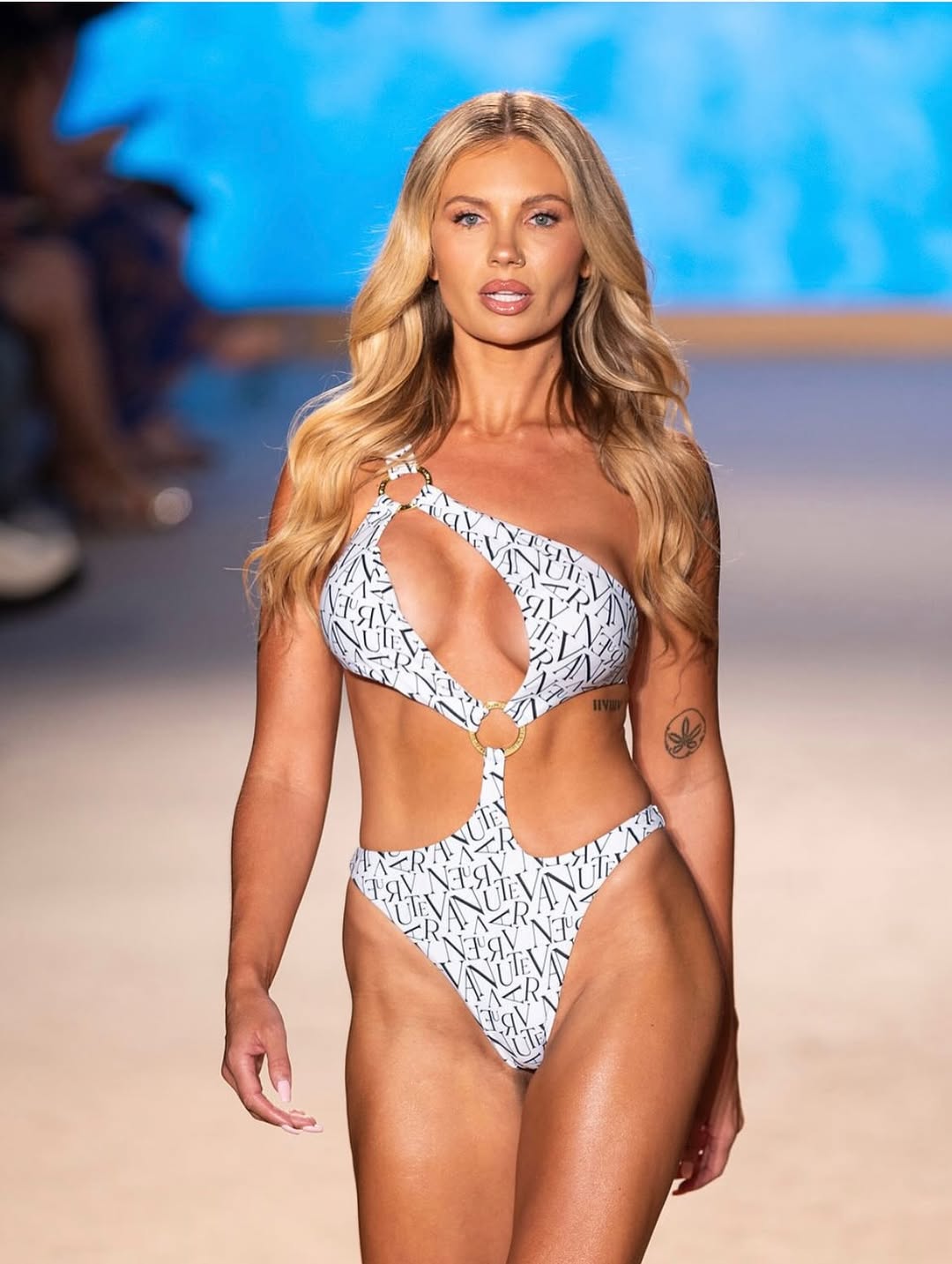 Model wearing a patterned swimsuit on a runway with a blurred background