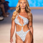 Model wearing a patterned swimsuit on a runway with a blurred background