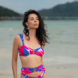 Woman in a colorful bikini standing on a beach with mountains in the background